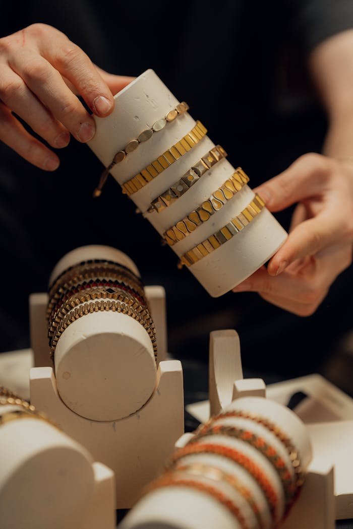 category-01 Close-up of hands displaying elegant gold and silver bracelets on a white display.